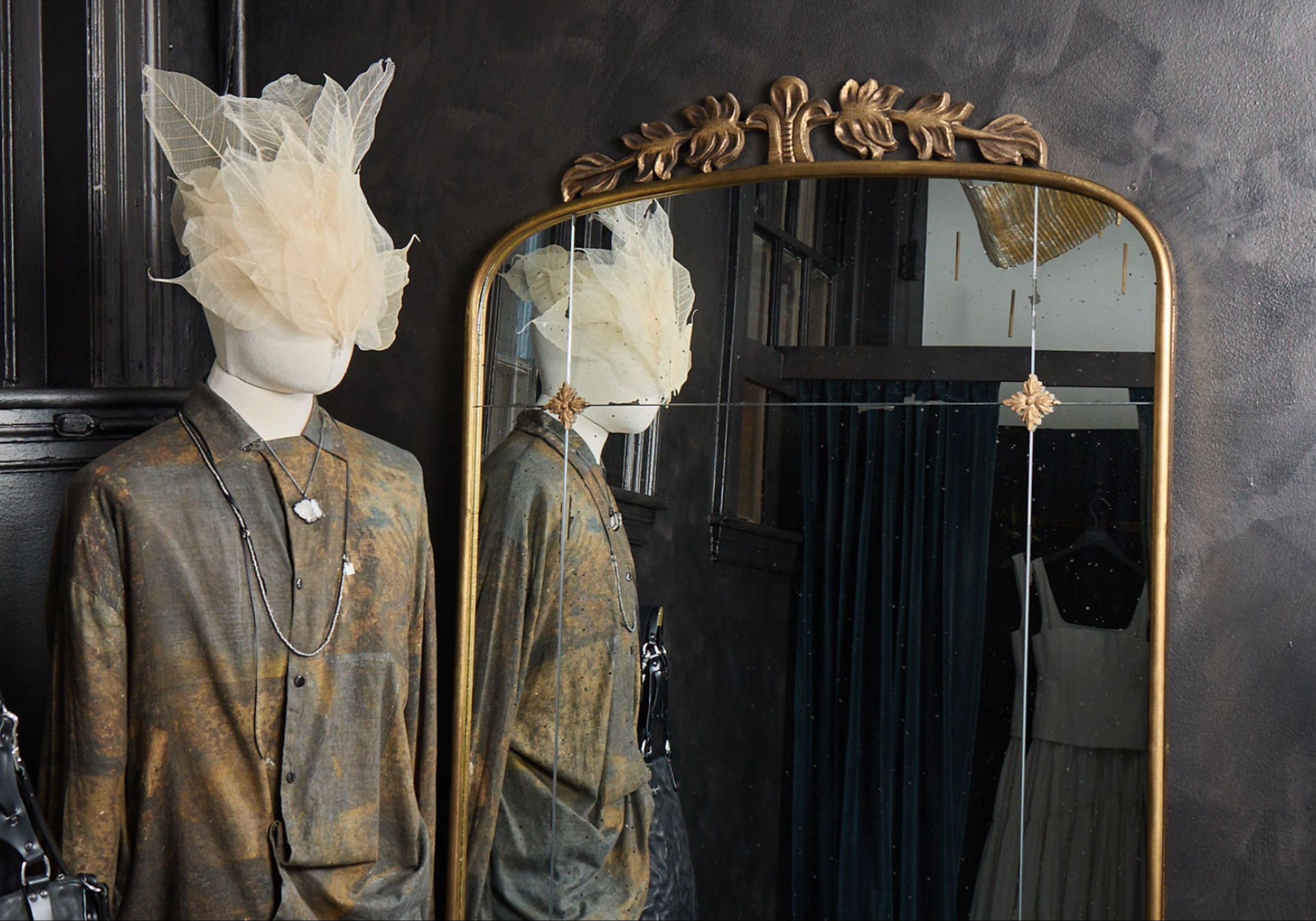 Mannequin wearing a suit with a floral headpiece in front of a mirror.